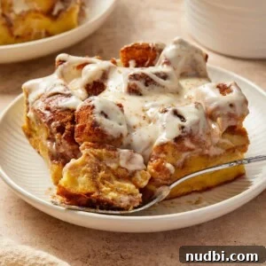 Slice of Brioche French toast bake with cinnamon and cream cheese frosting on plate.