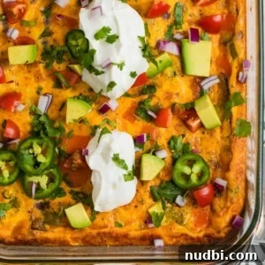 Chorizo egg bake in glass baking pan topped with sour cream, jalapeño, avocado, etc.