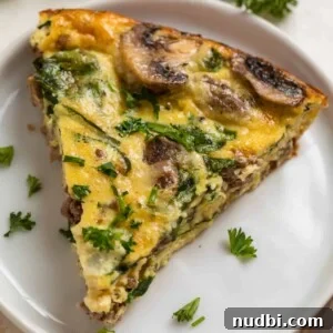 Crustless mushroom quiche with beef, swiss and spinach on white plate and topped with chopped parsley and chives.