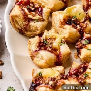 Festive Holiday Appetizers and Party Snacks Guide 2 Puff pastry brie bites on serving platter.