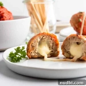 Festive Holiday Appetizers and Party Snacks Guide 14 Mozzarella stuffed turkey meatballs on plate with cheese stretching.