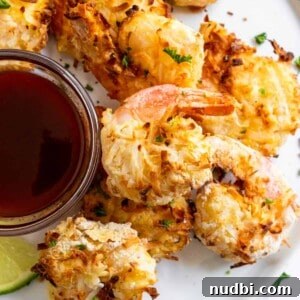 Festive Holiday Appetizers and Party Snacks Guide 15 Coconut shrimp on white plate with sauce.