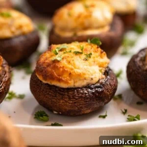 Festive Holiday Appetizers and Party Snacks Guide 7 Air fried stuffed mushrooms on white plate topped with chopped parsley.