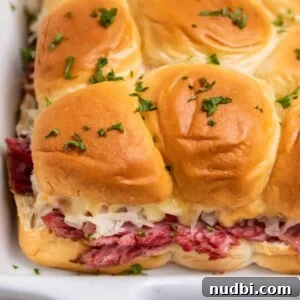 Festive Holiday Appetizers and Party Snacks Guide 10 Slow cooker reuben sliders in white pan.