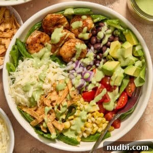 Shrimp Taco Salad with Creamy Cilantro-Lime Dressing 12 Taco salad in white bowl with sautéed shrimp, tomatoes, black beans, cheese and other ingredients.