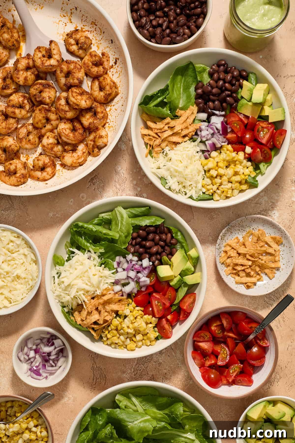 Shrimp Taco Salad with Creamy Cilantro-Lime Dressing 10 Salad bowls with greens, onion, corn and other ingredients prepared and ready to be topped with cooked shrimp.