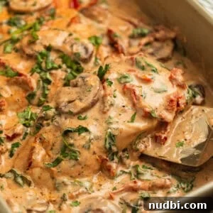 30-Minute Dinner Recipes You'll Love 19 Serving spatula picking up piece of creamy baked tuscan chicken topped with mushrooms, parsley, etc.
