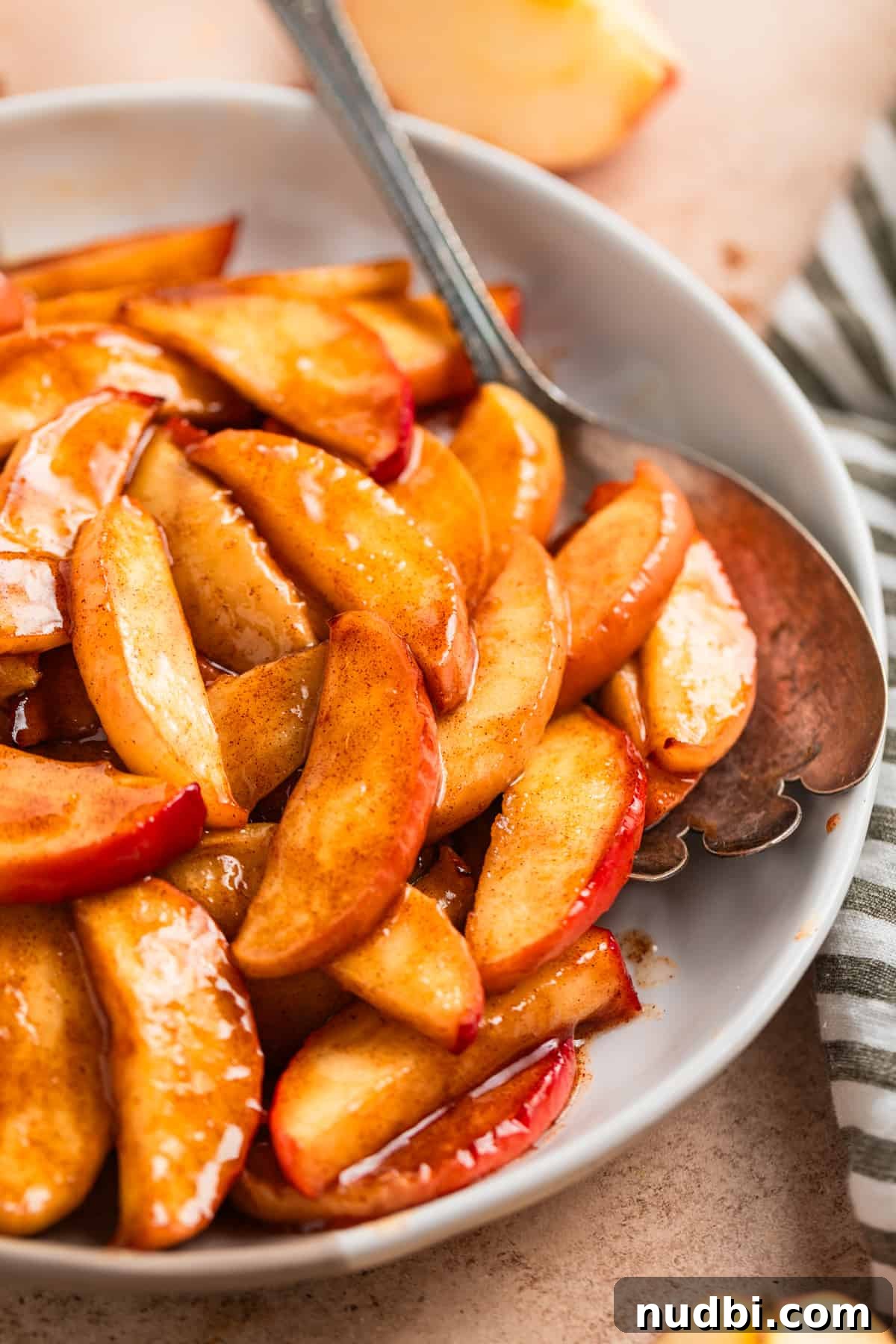 Crispy Caramelized Apples in the Air Fryer 2 Dish with cinnamon air fryer apples with serving spoon.