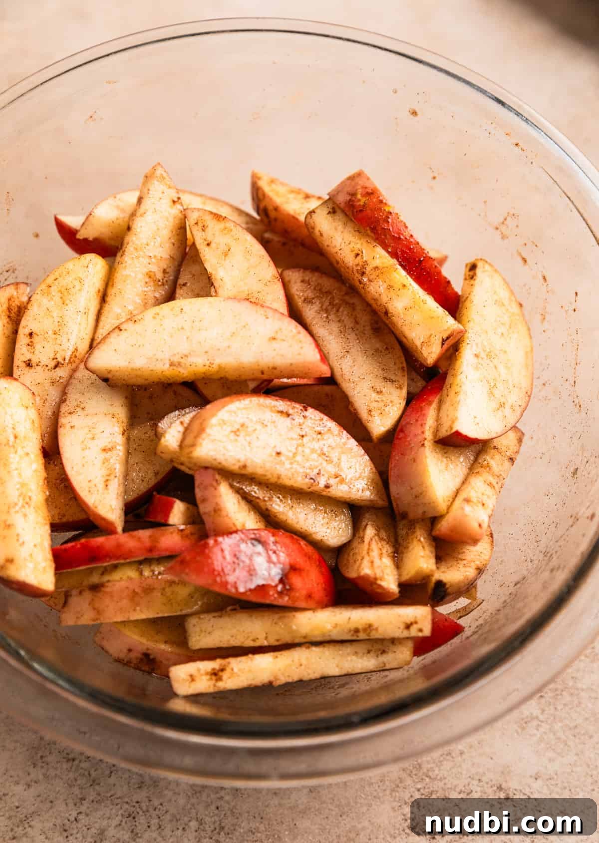 Crispy Caramelized Apples in the Air Fryer 3 Apples sliced and tossed in oil and cinnamon in glass mixing bowl