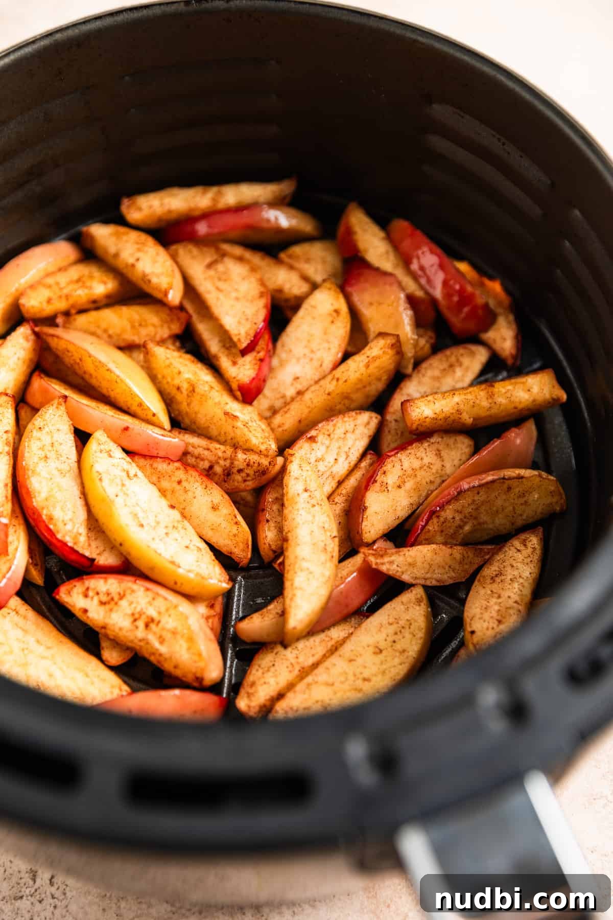 Crispy Caramelized Apples in the Air Fryer 5 Cooked apple slices in air fryer basket.