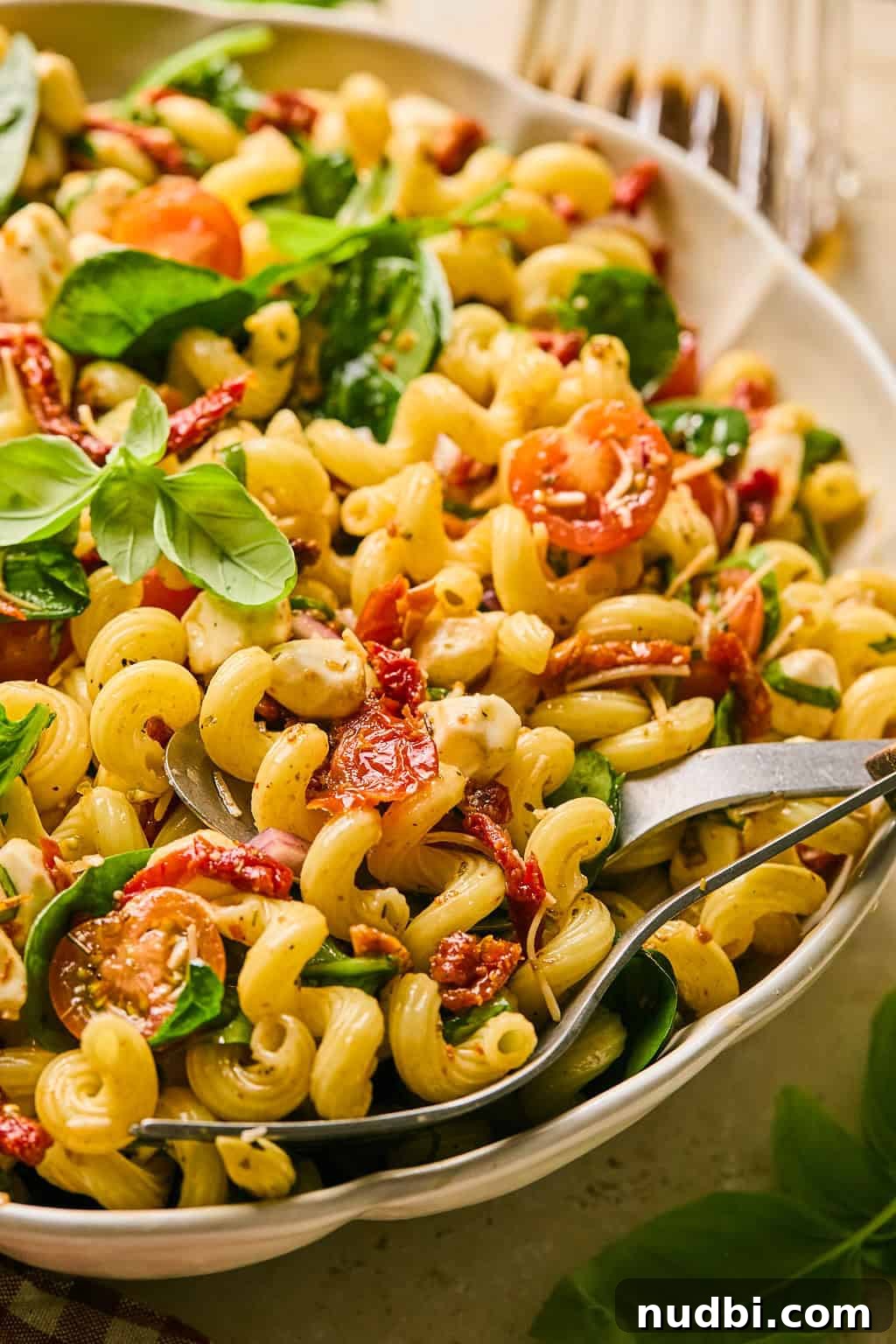 Sun-Dried Tomato Pasta Salad with Fresh Basil & Feta 9 Sun-dried tomato pasta salad in white dish topped with freshly chopped basil.