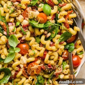 Sun-Dried Tomato Pasta Salad with Fresh Basil & Feta 10 Pasta salad with sun dried tomatoes, spinach, basil and other ingredients in serving bowl.