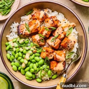 Air fryer salmon bites served with bang bang sauce over top and served on rice.