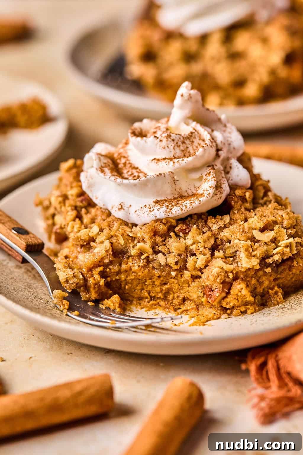 Ultimate Pumpkin Pie Crumble Recipe with a Buttery Streusel Topping 2 Pumpkin pie crumble slice on plate with whipped cream on top and fork propped beside it.