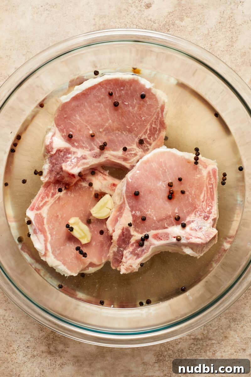 Creamy Mushroom Pork Chops with Garlic and Thyme 7 Pork chops in brine in glass bowl.