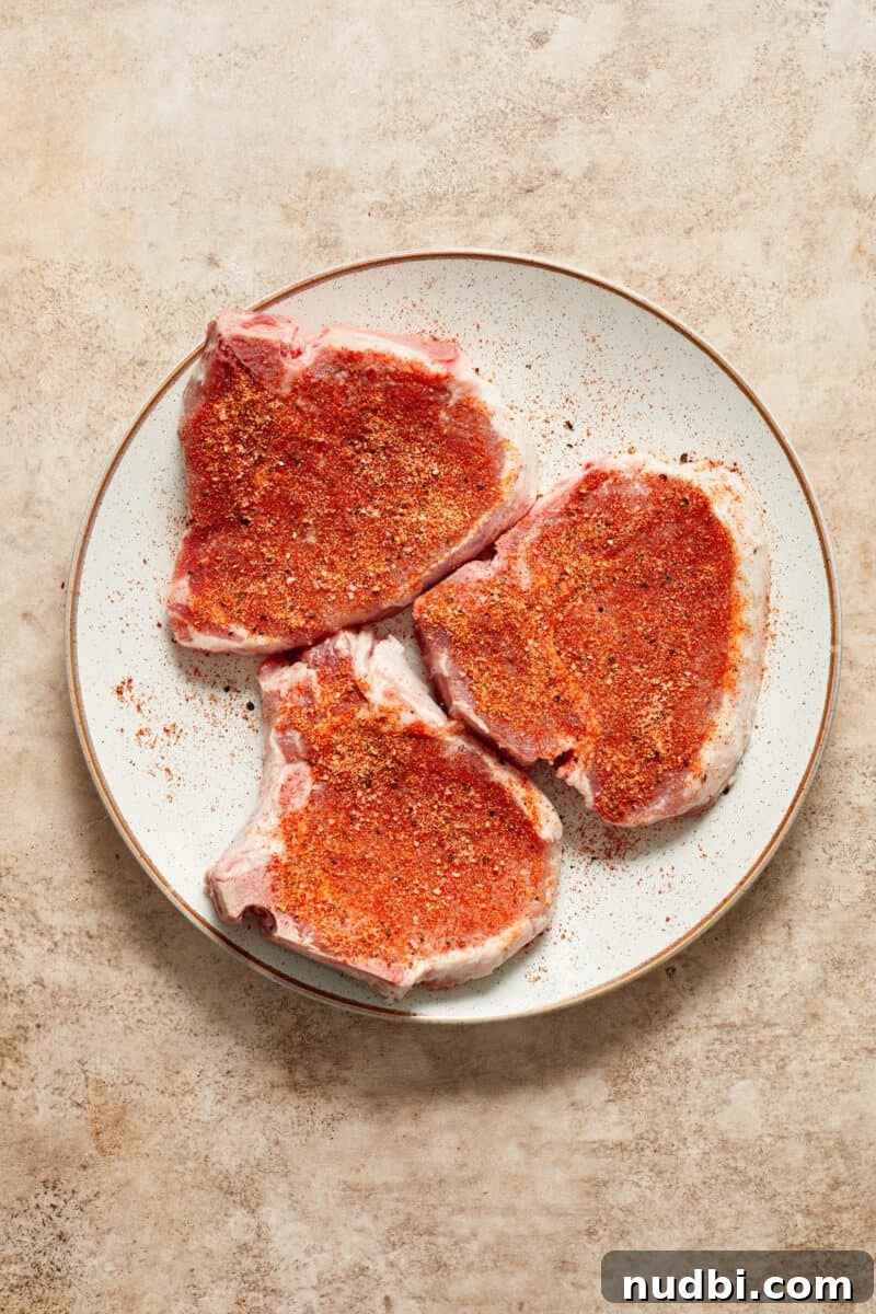 Creamy Mushroom Pork Chops with Garlic and Thyme 8 Pork chops with seasoning on white plate.