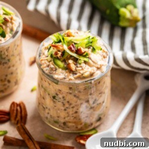 Creamy Overnight Oats Recipes for Quick Healthy Breakfasts 13 Glass jar with zucchini bread overnight oatmeal and white spoons beside it along with pecans and cinnamon sticks.
