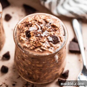 Creamy Overnight Oats Recipes for Quick Healthy Breakfasts 9 Chocolate overnight oatmeal in jar with spoon and chocolate pieces beside it.