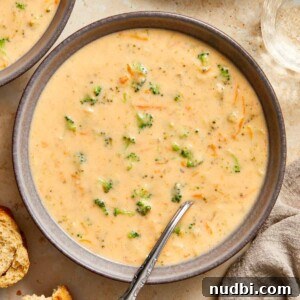 Cozy Dinner Recipes for Comforting Weeknight Meals 28 Gray ceramic bowl with broccoli cheddar soup served with spoon.