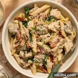Cozy Dinner Recipes for Comforting Weeknight Meals 4 Bowl of pasta with cream sauce, chicken, mushrooms, spinach and fork propped in bowl.