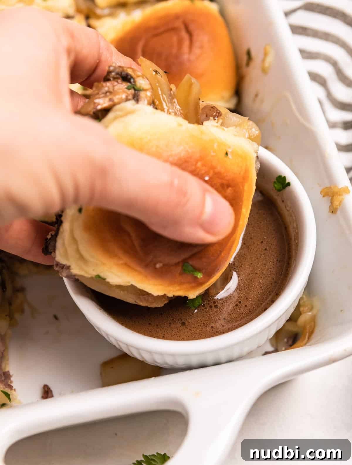 French Dip Sliders Recipe with Savory Au Jus for Dipping 12 French dip slider dipped in au jus.