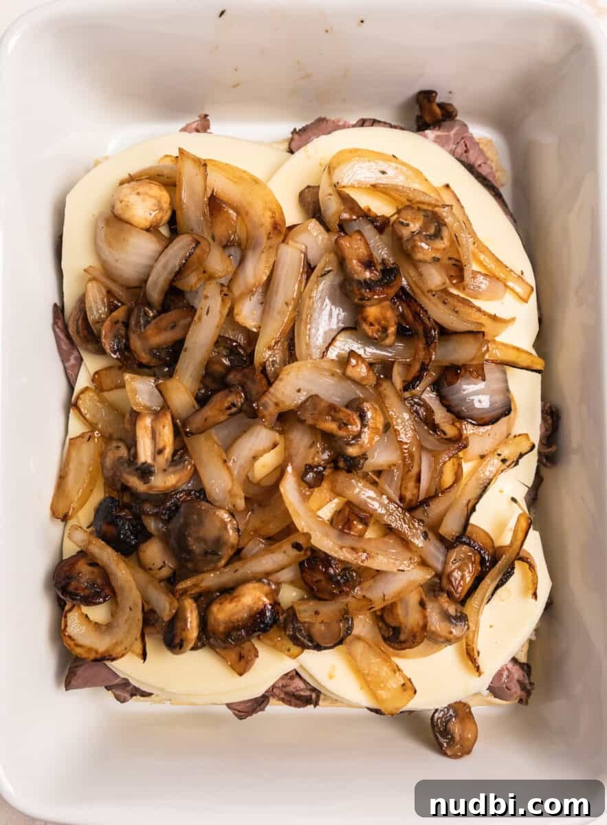 French Dip Sliders Recipe with Savory Au Jus for Dipping 8 Caramelized onions and mushrooms on top of cheese and beef.