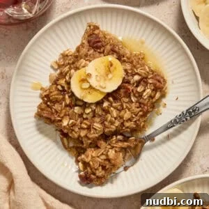 Banana bread baked oatmeal on plate with sliced bananas on top.