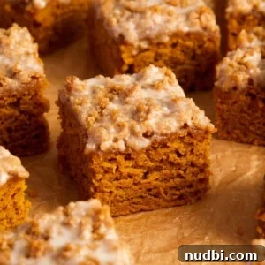 Slices of cinnamon streusel topped pumpkin coffee cake on crinkled brown parchment paper.