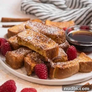 Plate with air fryer French toast sticks dusted with powdered sugar.