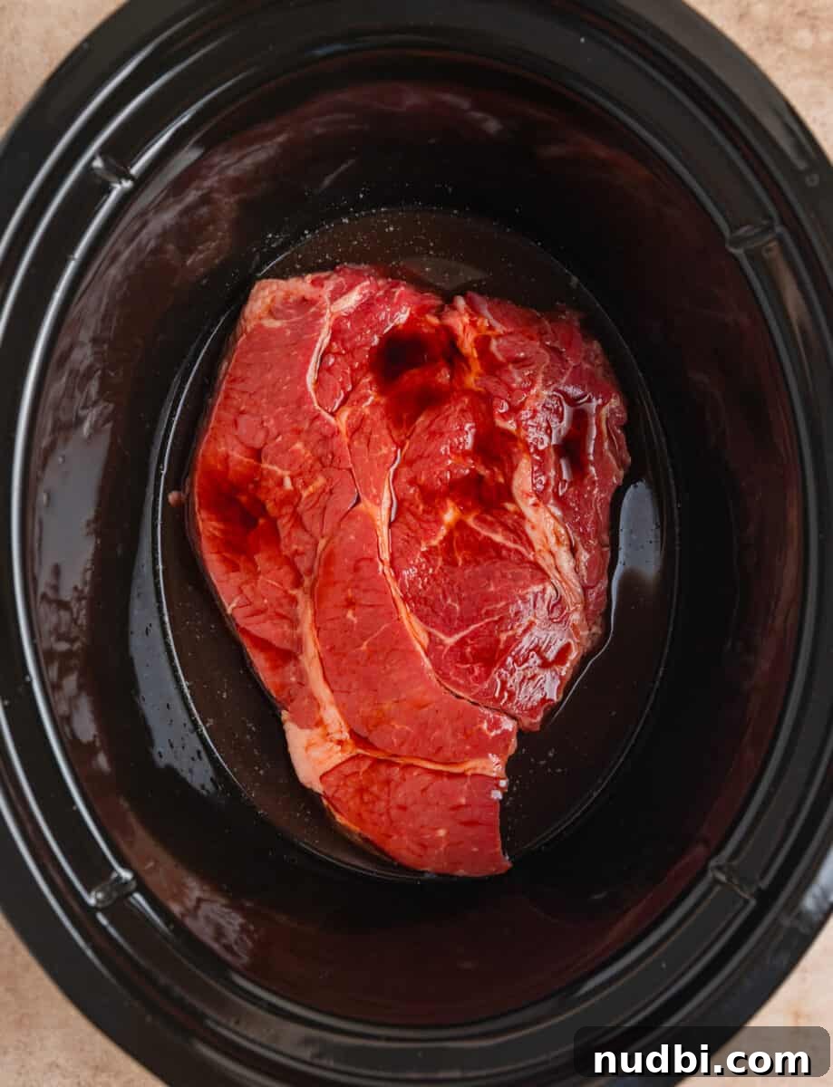 Slow-Cooker Shredded Beef Recipe for Tender, Flavorful Meals 5 Soy sauce and other liquid poured over beef chuck roast in crock pot.