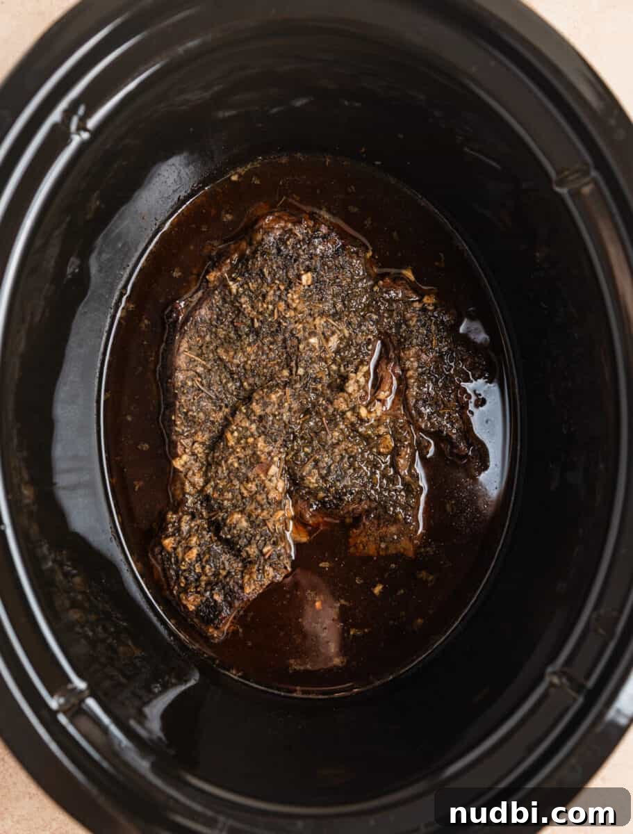 Slow-Cooker Shredded Beef Recipe for Tender, Flavorful Meals 7 Overhead view of cooked chuck roast in juices in slow cooker.