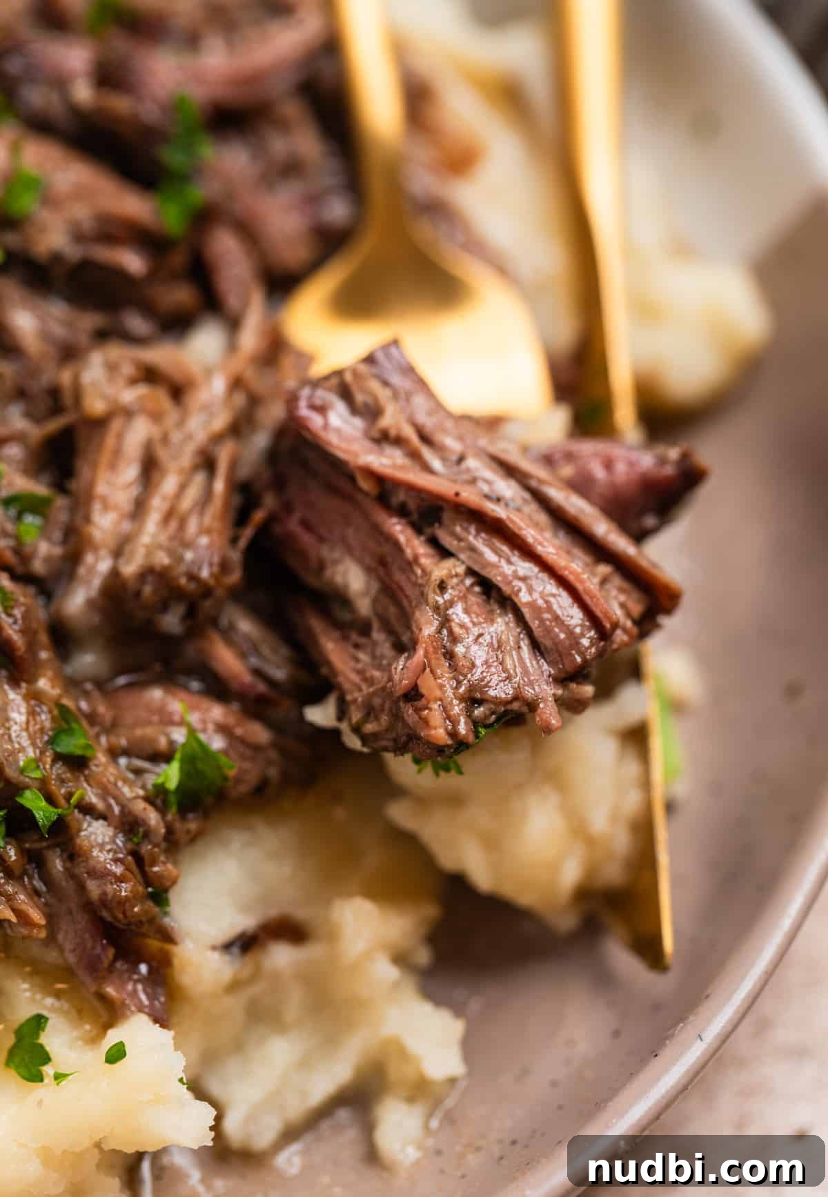 Slow-Cooker Shredded Beef Recipe for Tender, Flavorful Meals 9 Piece of shredded beef on fork with mashed potatoes on plate.