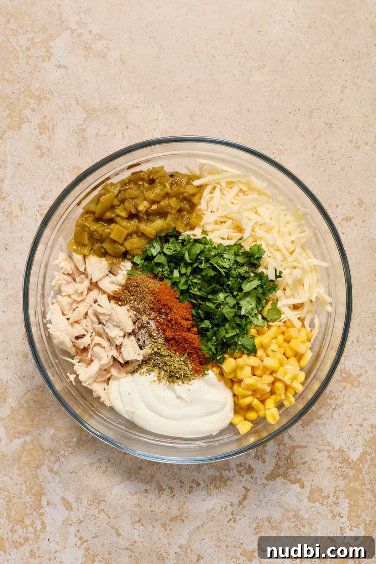 Authentic Green Salsa Chicken Enchiladas Recipe 4 Chicken, cilantro, corn, spices, sour cream, cheese and other ingredients for chicken enchiladas in bowl.