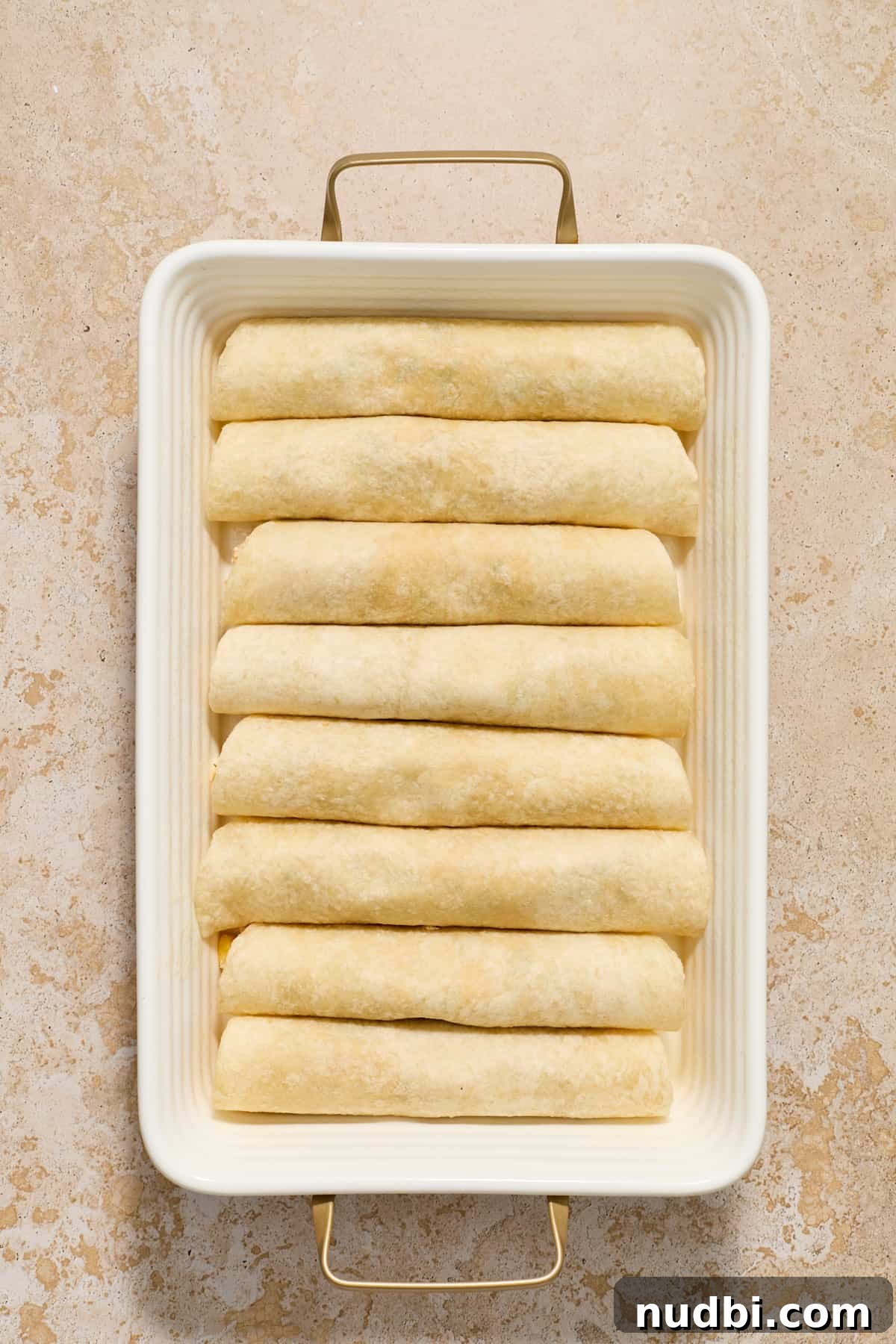 Authentic Green Salsa Chicken Enchiladas Recipe 7 Rolled tortillas with green chicken enchilada mixture in pan.