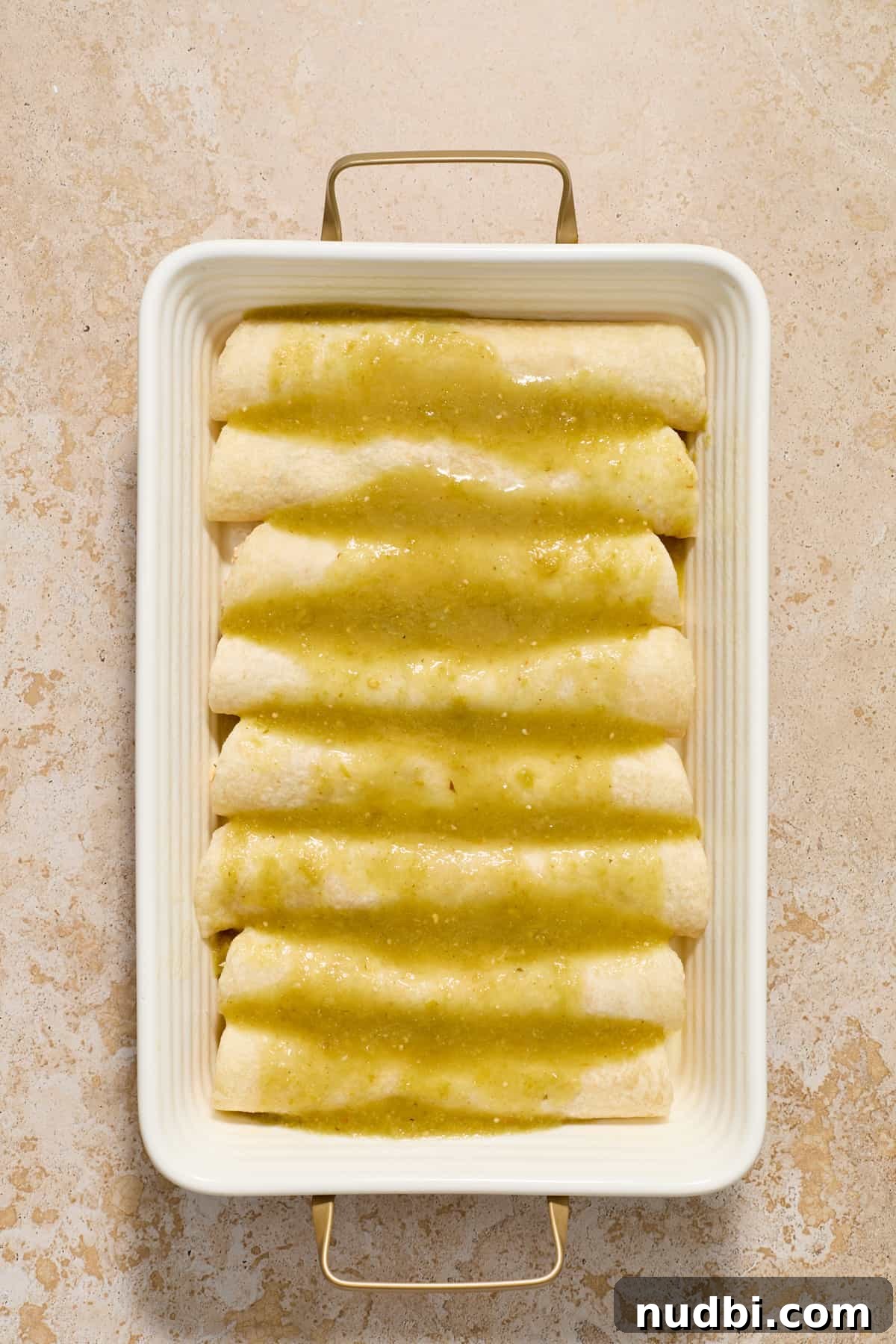 Authentic Green Salsa Chicken Enchiladas Recipe 8 Chicken enchiladas in pan with green enchiladas sauce on top.