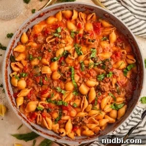 Ground beef pasta in skillet topped with basil.