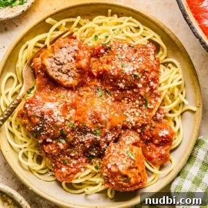 Plate with spaghetti and meatballs topped with fresh parmesan.