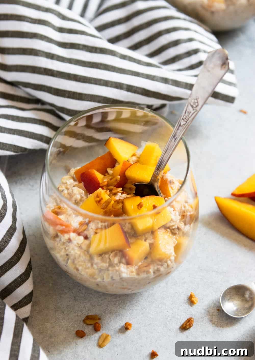 Peach Pie Overnight Oats Recipe for Quick Morning Meals 2 Peach Overnight Oats in glass with spoon and fresh peaches.