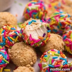 No-Bake Mini Cheesecake Bites: Easy Dessert Balls Recipe 11 Bite shot of sprinkle covered no bake cheesecake ball arranged with other cheesecake balls.