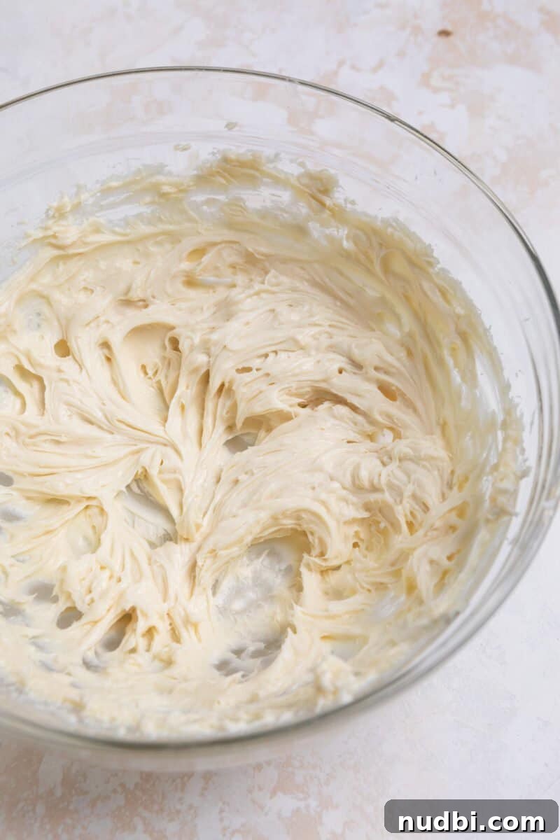 No-Bake Mini Cheesecake Bites: Easy Dessert Balls Recipe 4 Cream cheese whipped with sugar and vanilla in glass mixing bowl.
