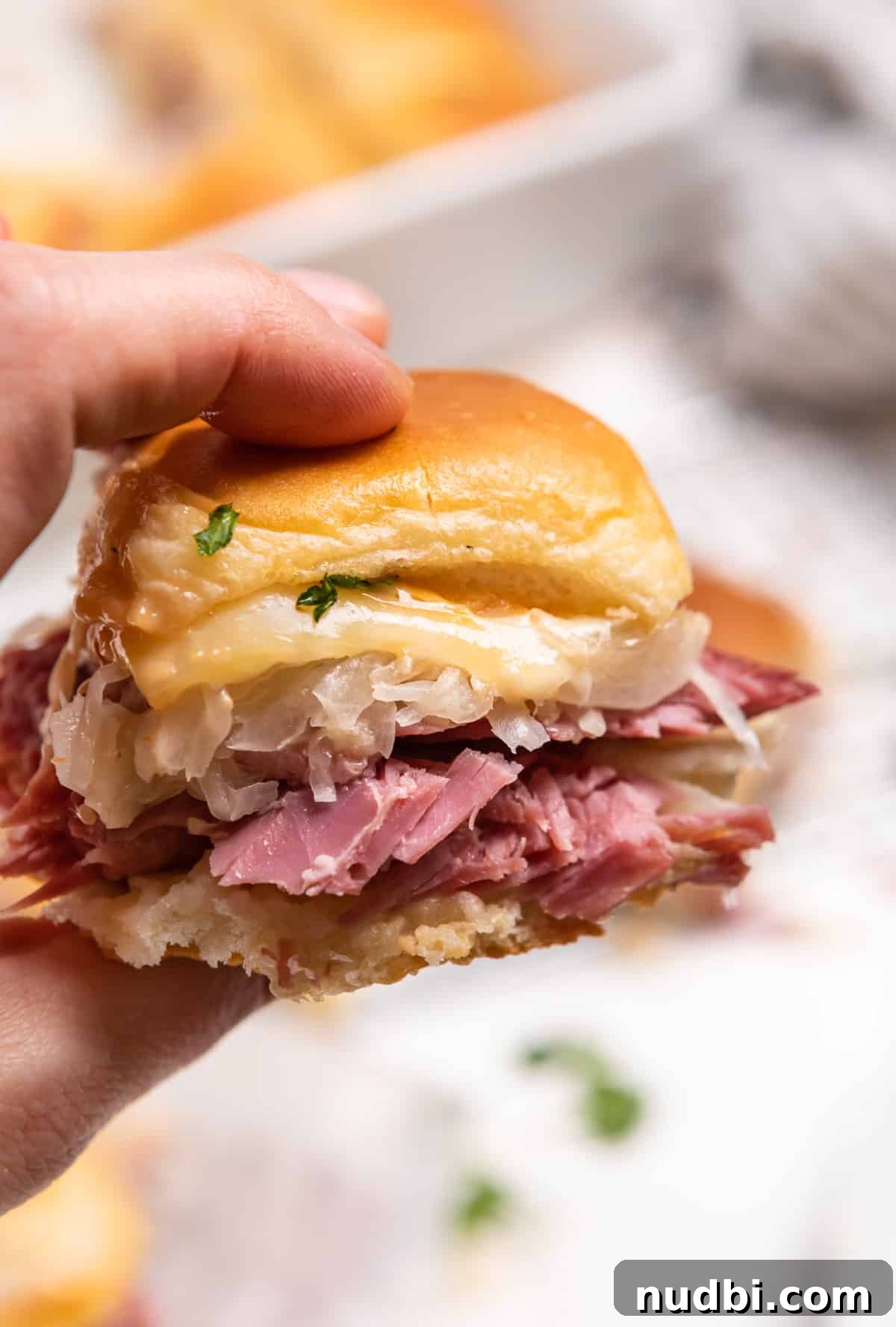 Classic Reuben Sliders with Melted Swiss and Tangy Sauerkraut 11 Reuben slider held up to show close up of sandwich.