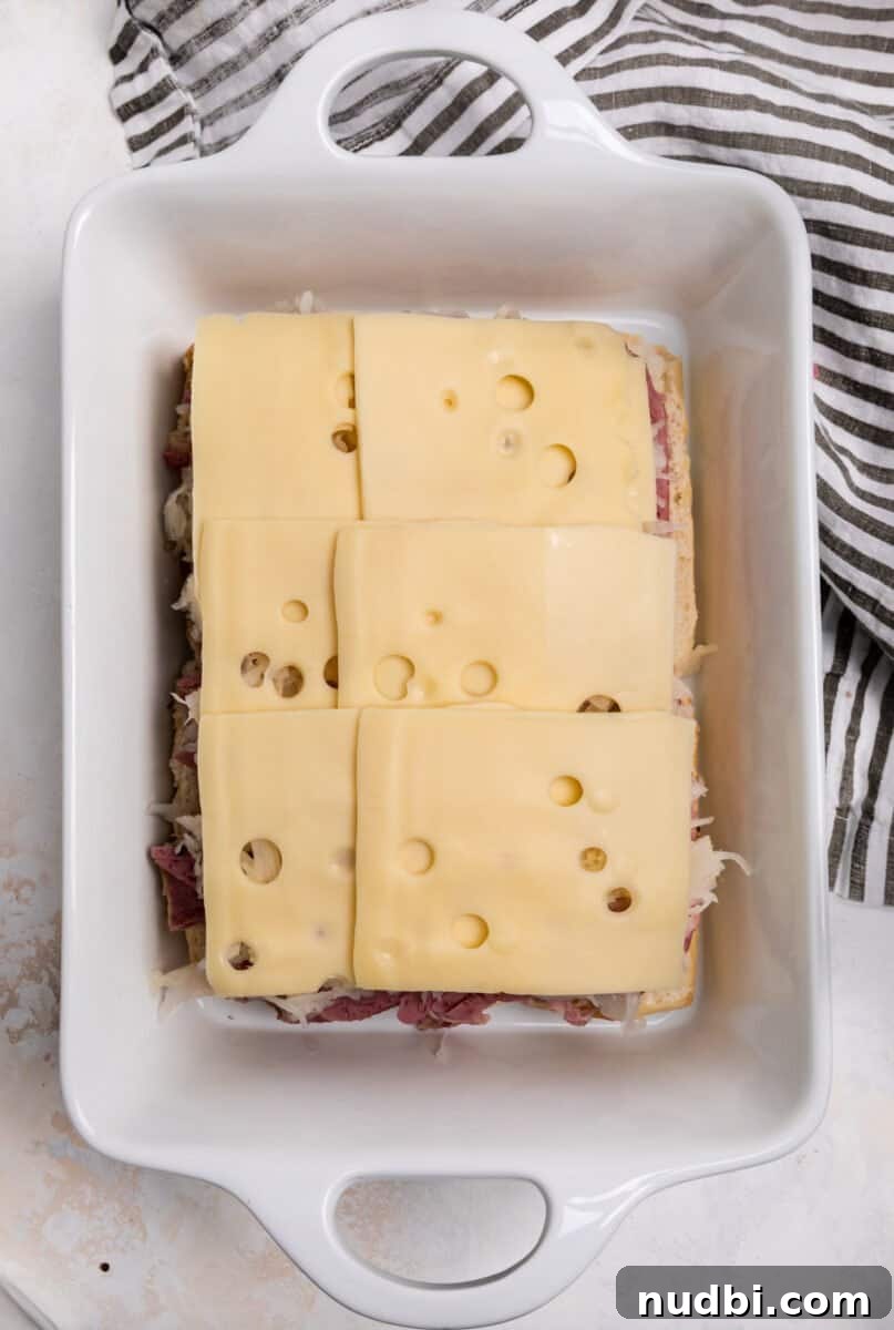 Classic Reuben Sliders with Melted Swiss and Tangy Sauerkraut 8 Swiss cheese on top of sauerkraut and corned beef.