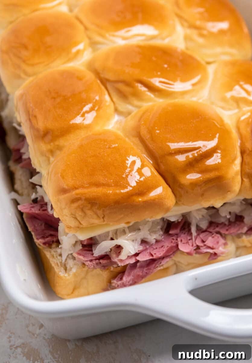 Classic Reuben Sliders with Melted Swiss and Tangy Sauerkraut 9 Buttered tops of Hawaiian rolls with corned beef, sauerkraut, swiss cheese in baking pan.