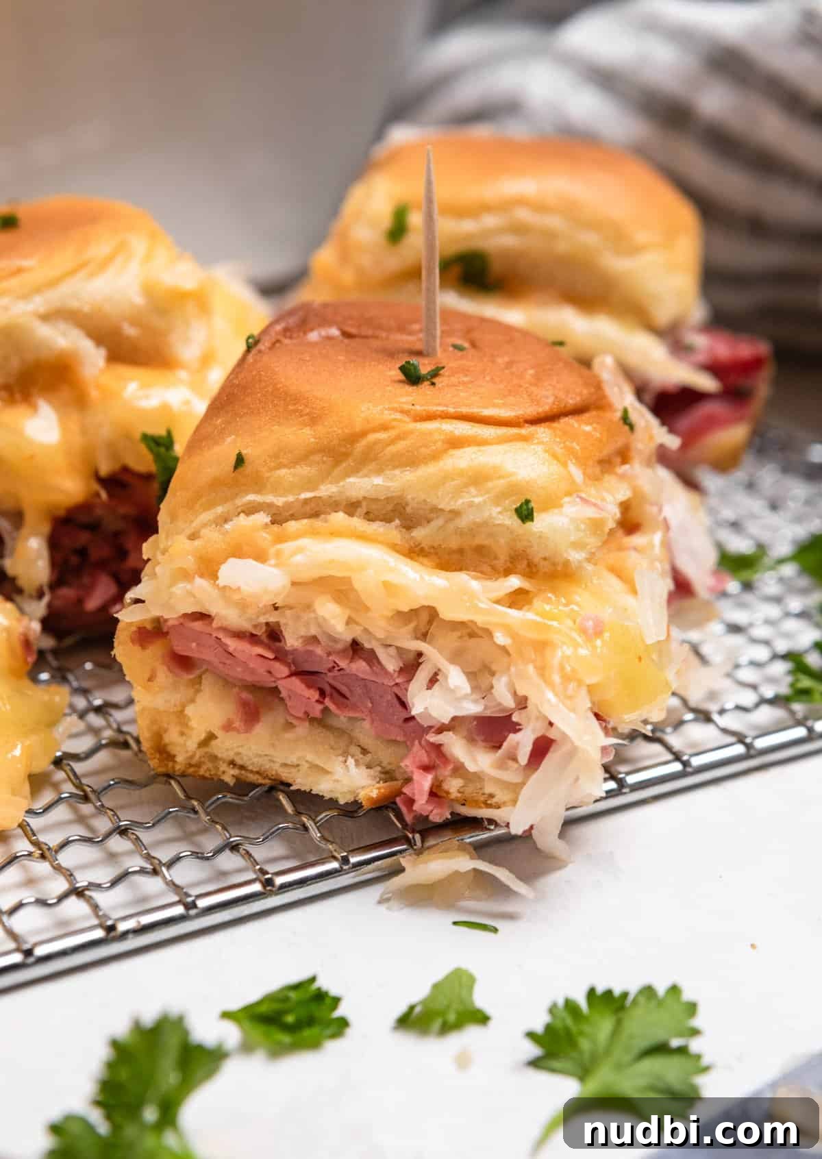 Classic Reuben Sliders with Melted Swiss and Tangy Sauerkraut 10 Reuben slider held up to show close up of sandwich.