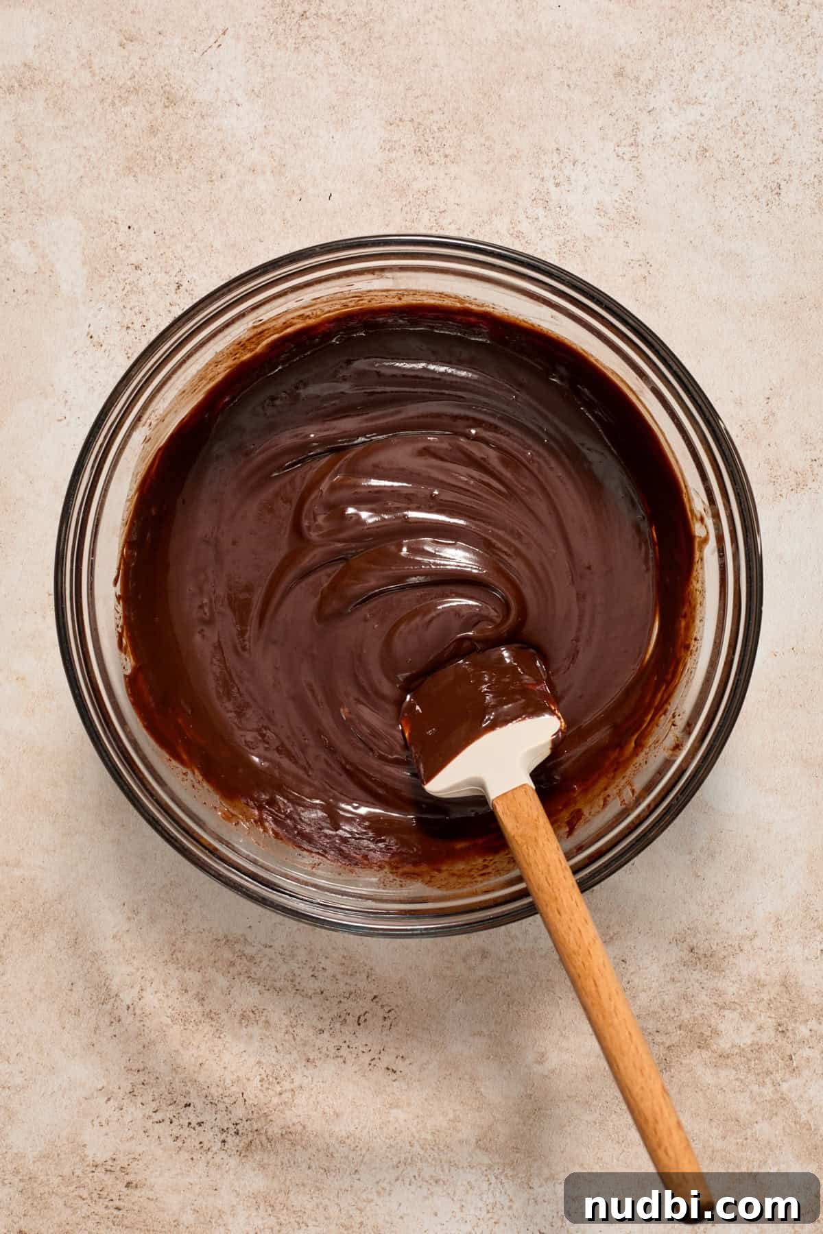 No-Bake Chocolate Cream Pie Recipe for Rich, No-Fuss Dessert 9 Melted dark chocolate in glass mixing bowl with spatula.
