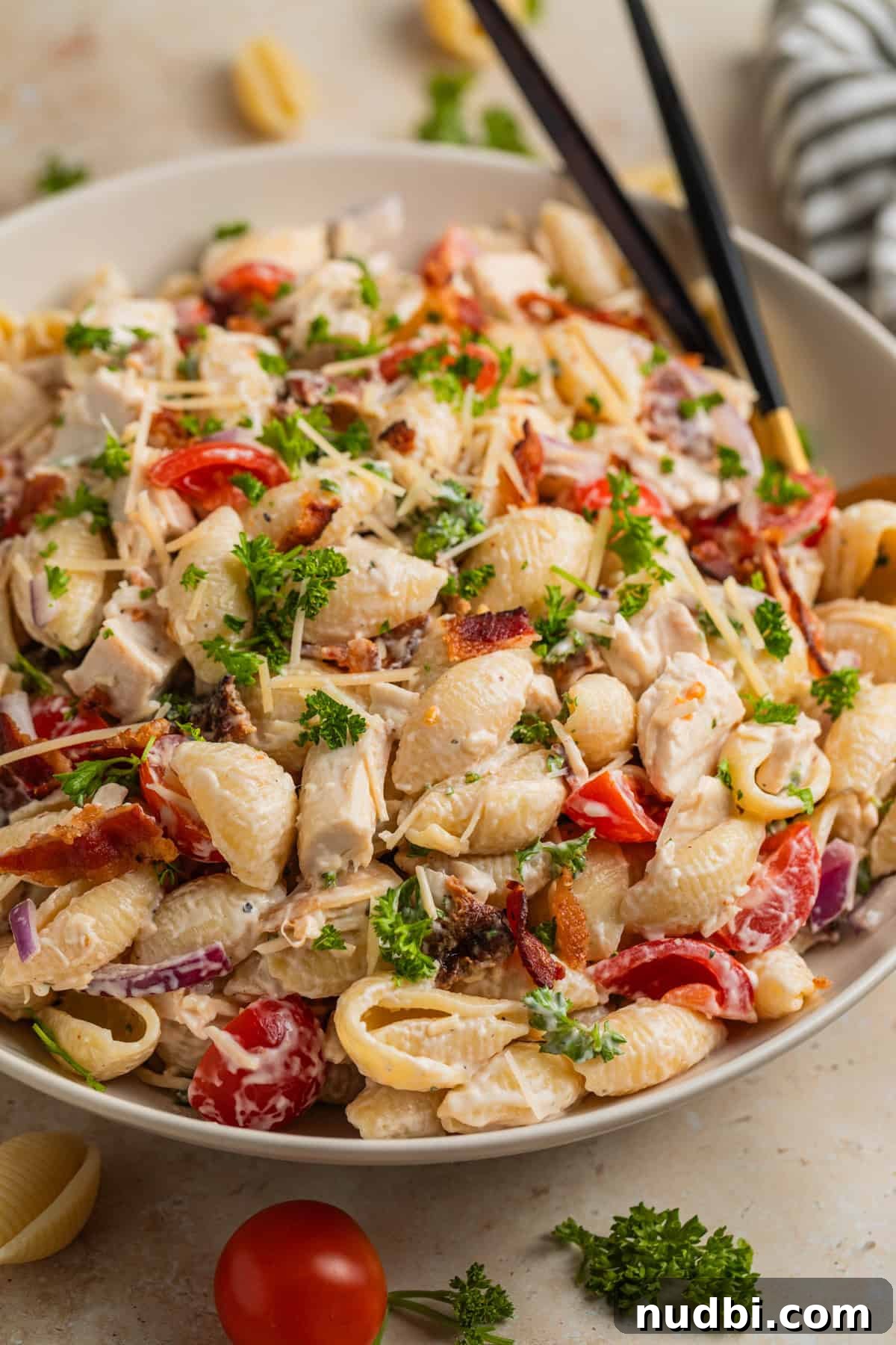 Chicken, Bacon & Ranch Pasta Salad Recipe for Summer Meals 2 Chicken bacon ranch pasta salad in white serving dish topped with parmesan and fresh parsley.