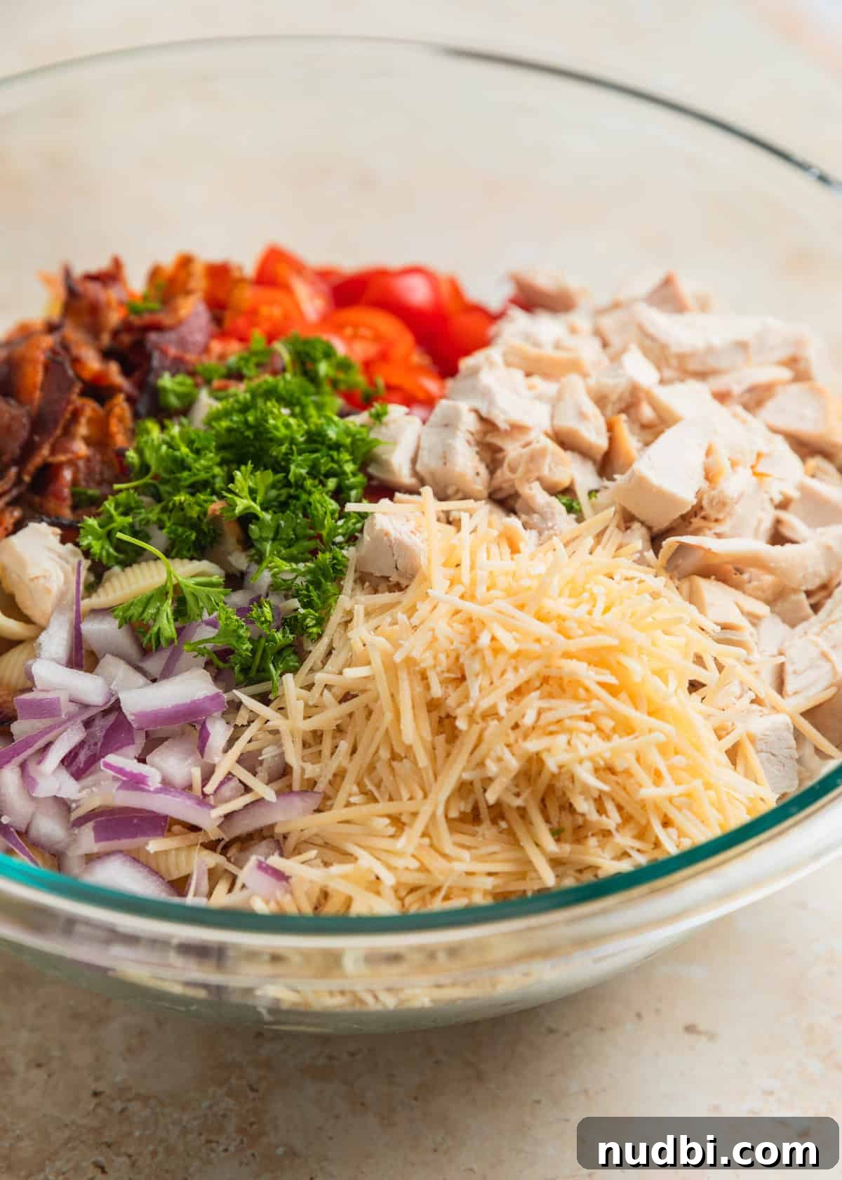 Chicken, Bacon & Ranch Pasta Salad Recipe for Summer Meals 6 Cooked pasta shells, quartered tomatoes, chicken, chopped bacon and parsley in bowl.