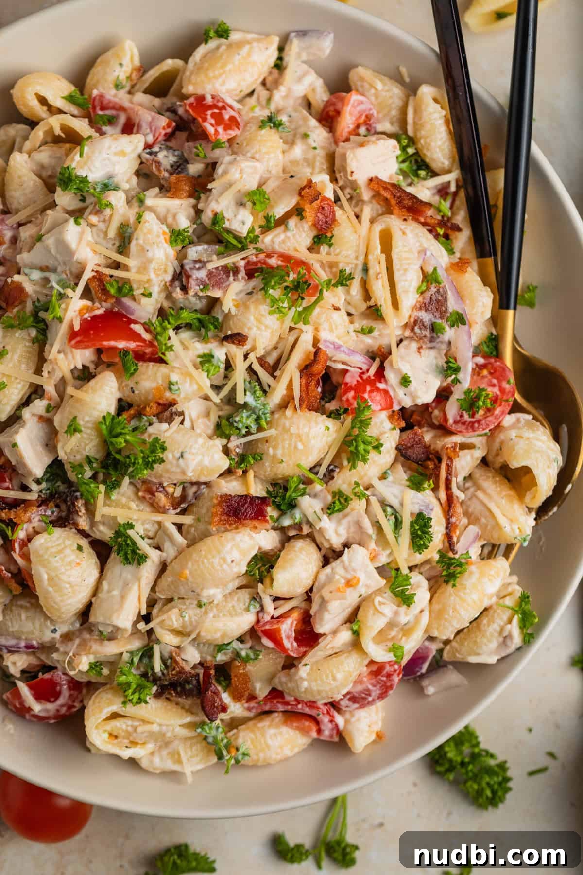 Chicken, Bacon & Ranch Pasta Salad Recipe for Summer Meals 9 White bowl with Chicken bacon ranch pasta salad with wood spoon and linen beside it.