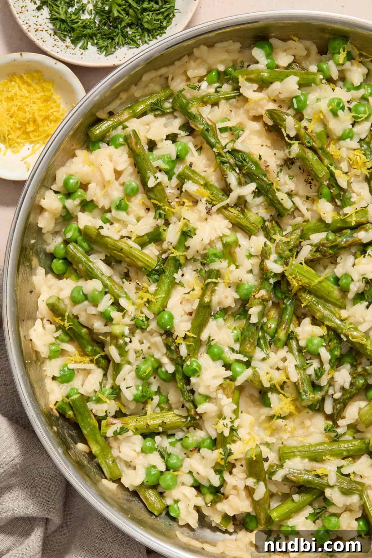 Creamy Spring Risotto with Peas and Asparagus 2 Creamy risotto with peas and asparagus in pan topped with parmesan and lemon zest.