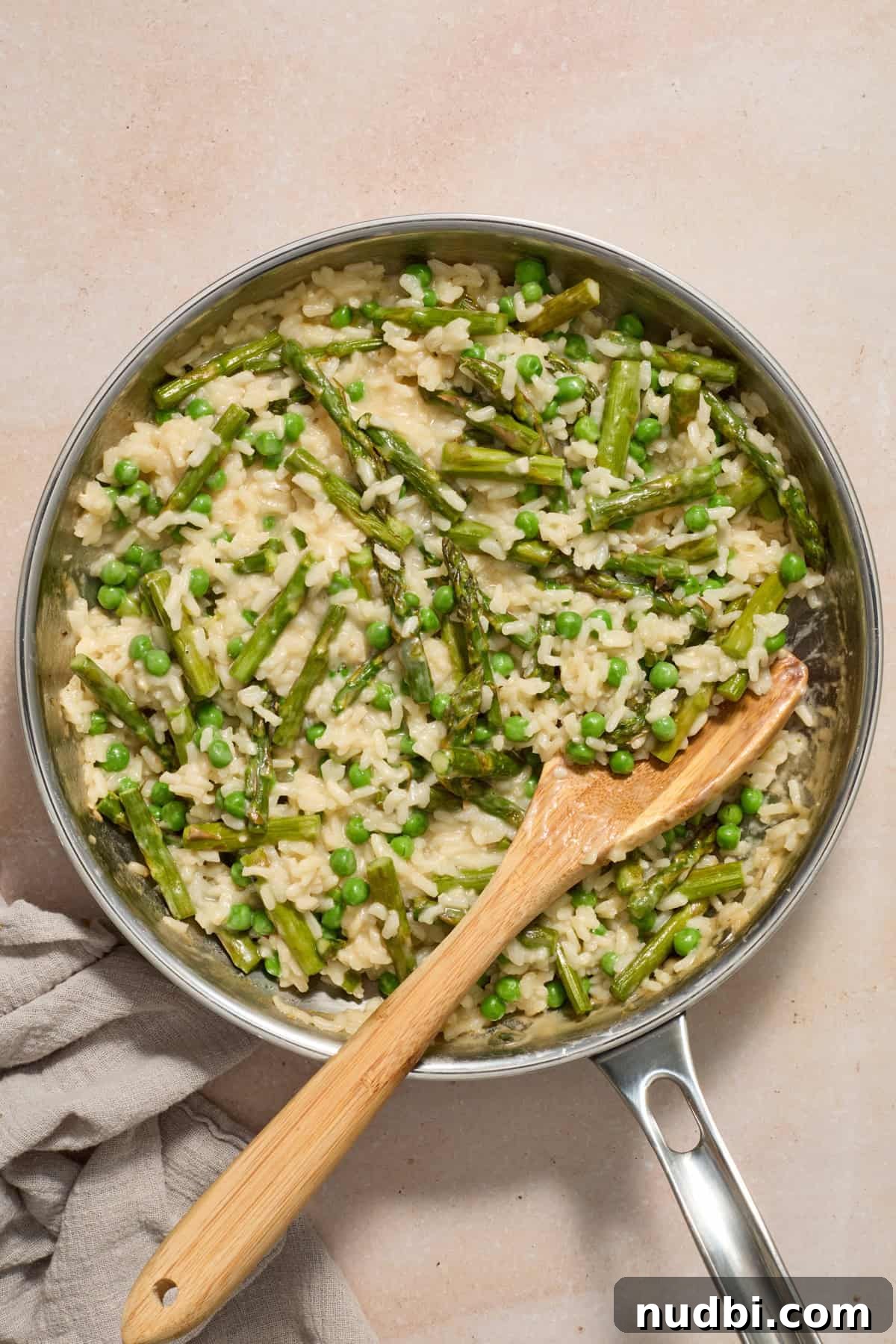 Creamy Spring Risotto with Peas and Asparagus 12 Pea and asparagus risotto in pan with towel beside pan.